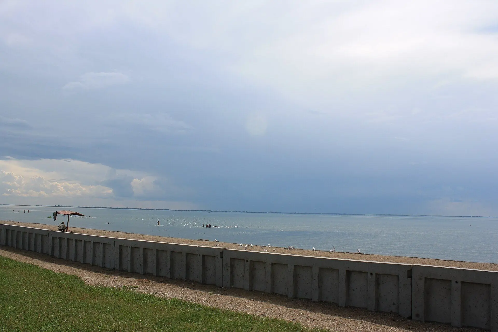 Lakeshore beach and seawall under stormy sky