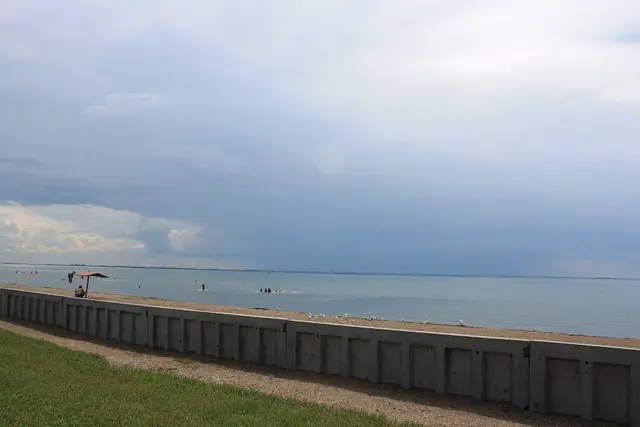 Lakeshore beach and seawall under stormy sky